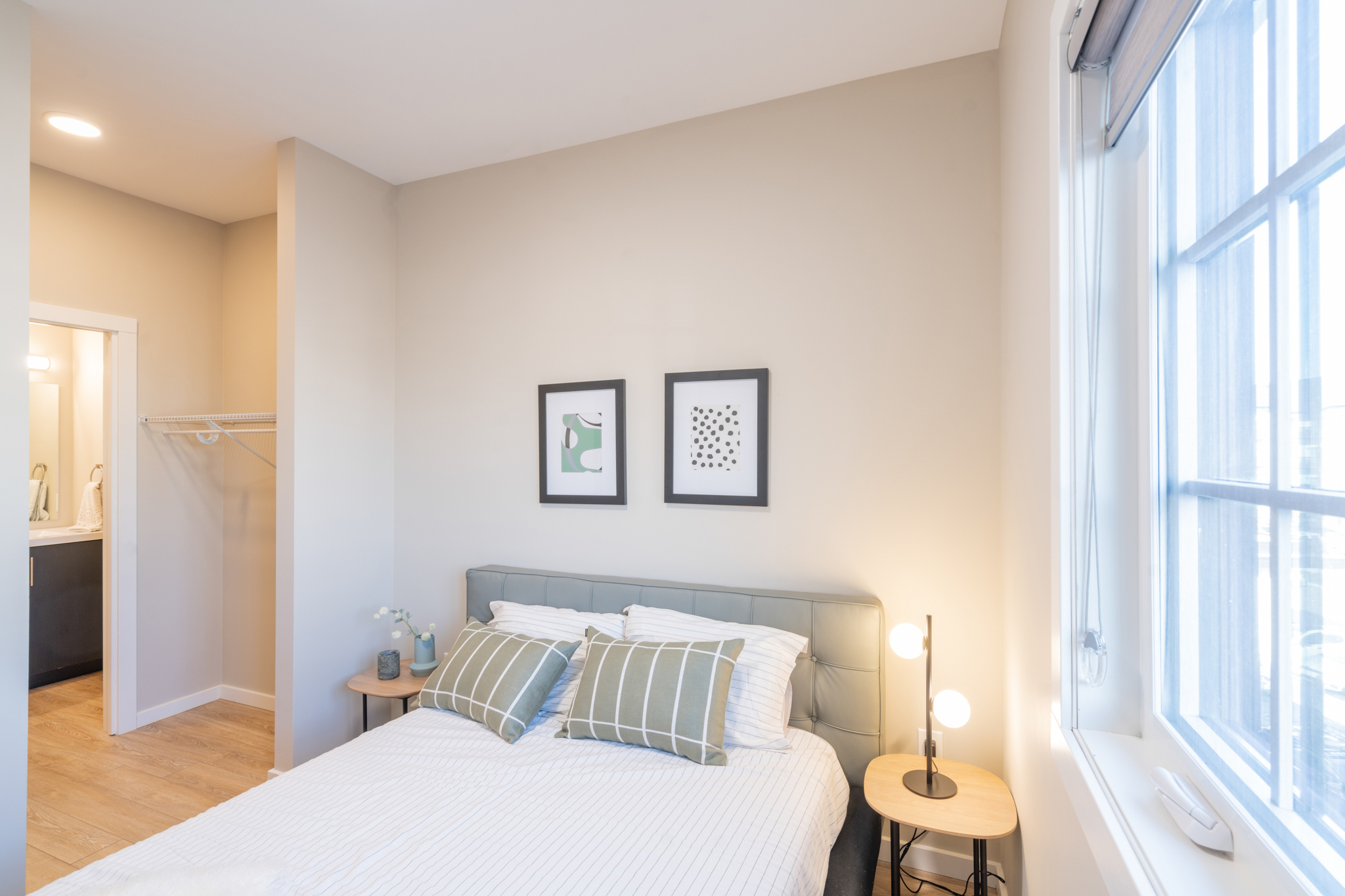 Shows the bedroom of a unit, with a bed and pictures hanging on the wall.