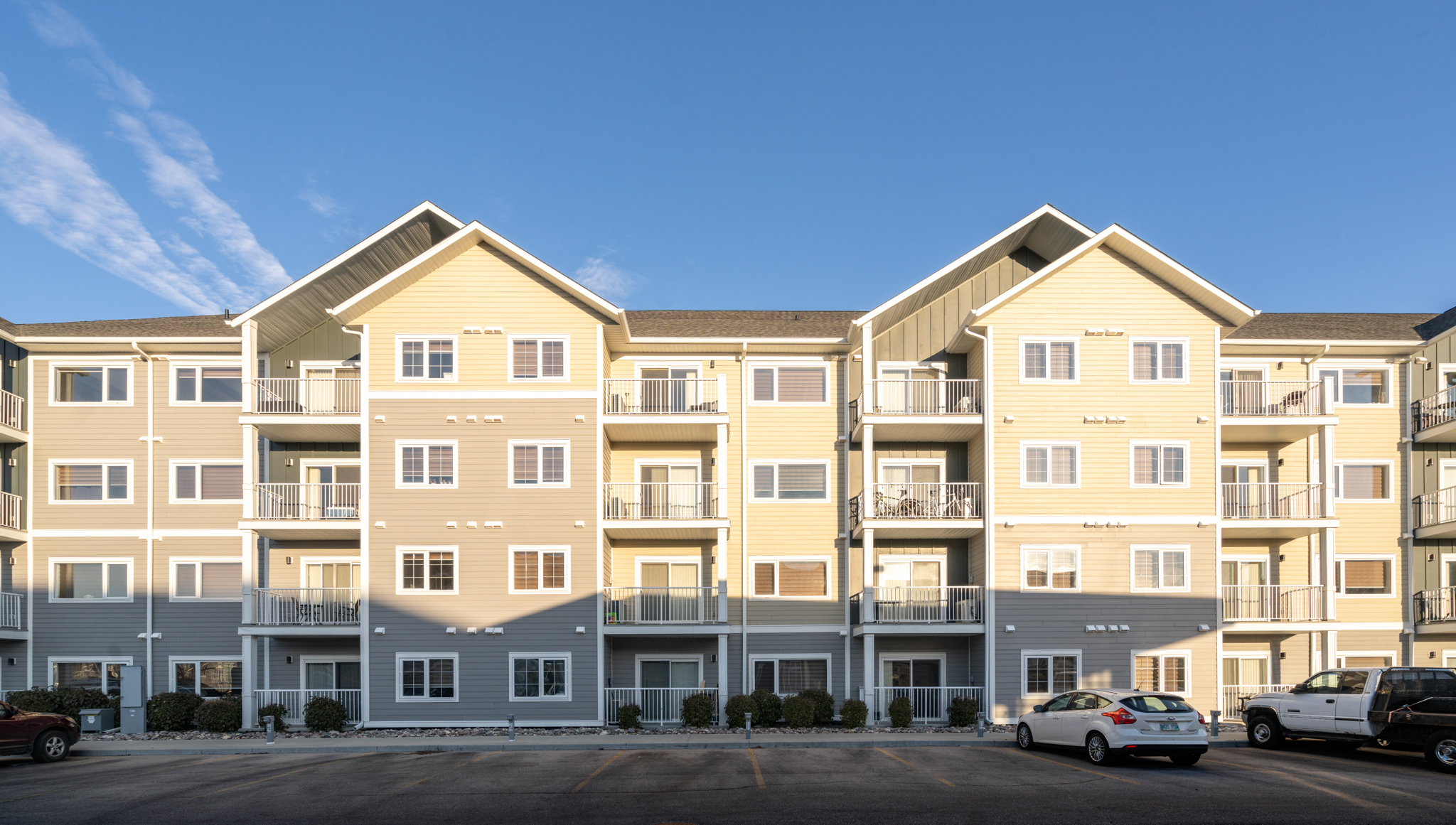 Image of the exterior of the back of the building, showing parking spaces and rear balconies.