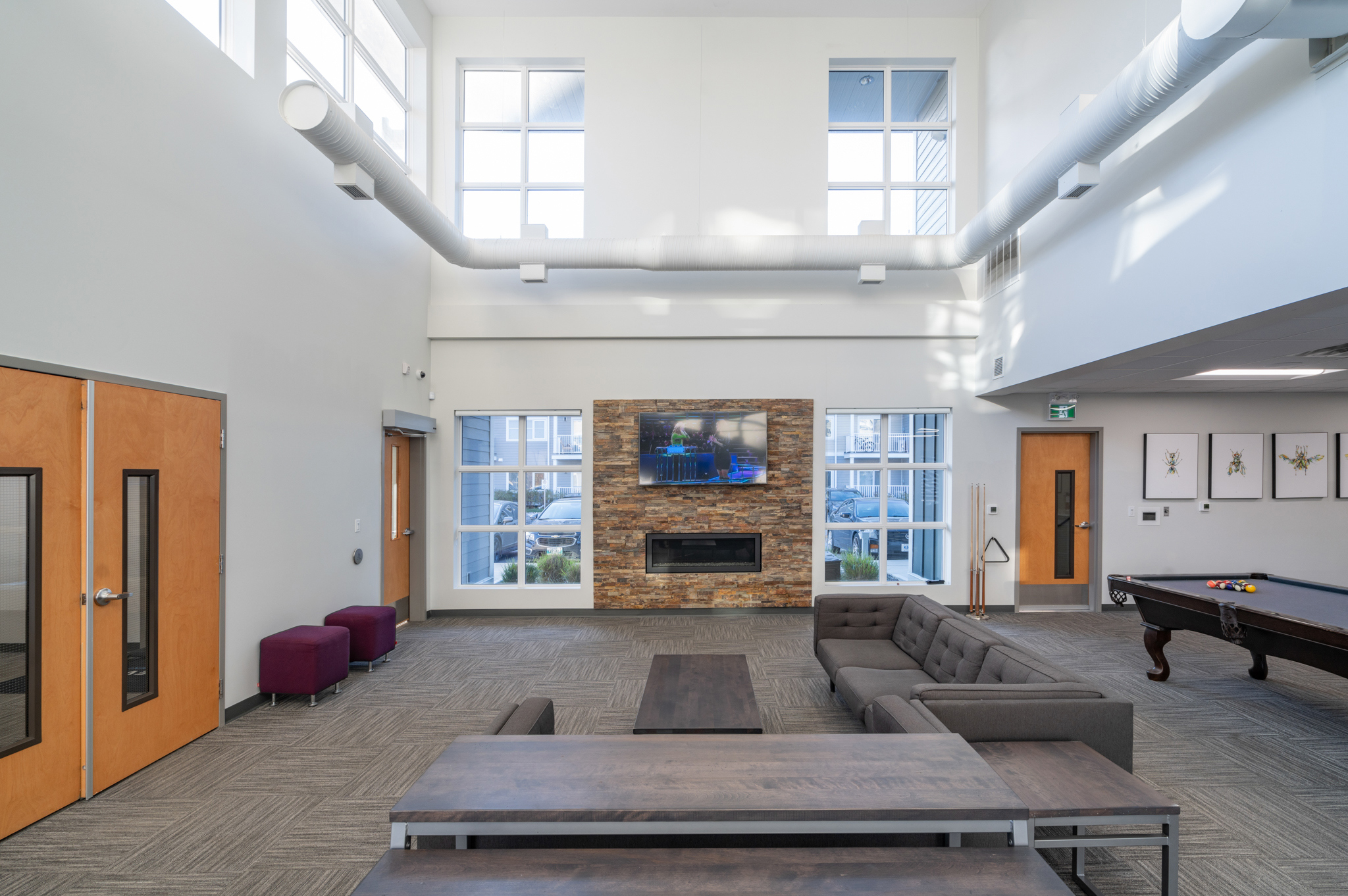 Image of the lobby showing couches, an electronic fireplace and a tv.