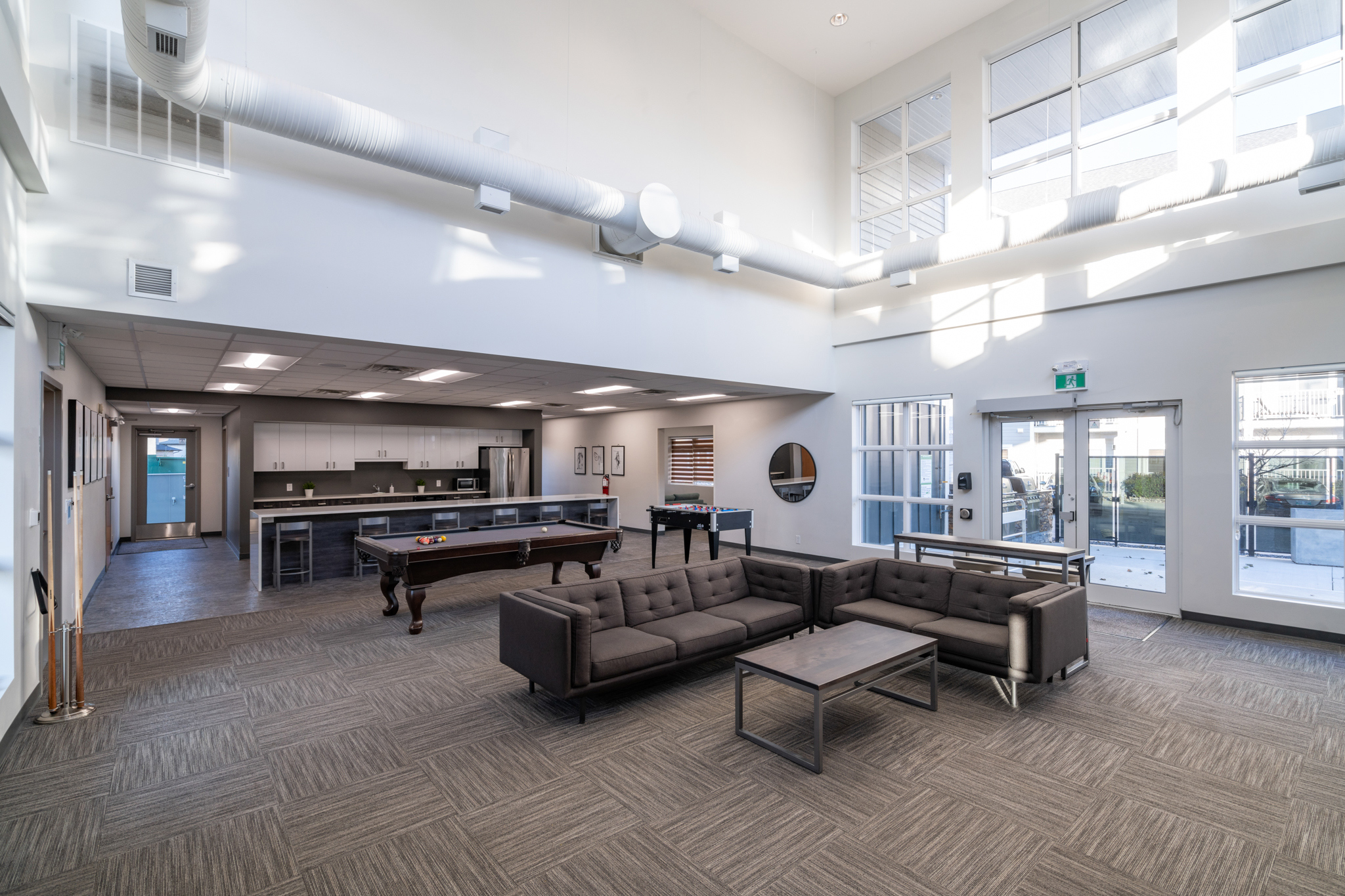 Image of the lobby area, showing couches, a pool table, a foosball table and a kitchen area.