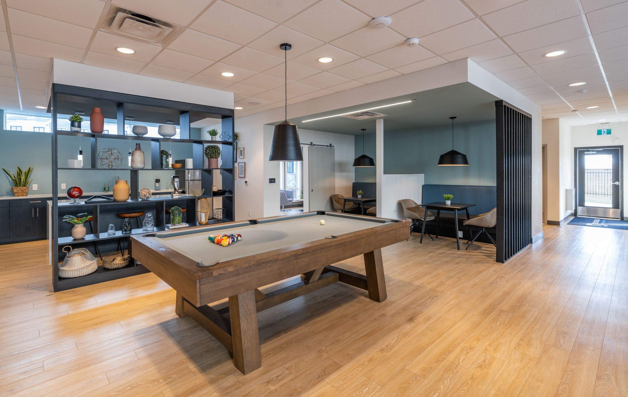 Image of the lobby, showing the pool table and a wooden shelf with various plants and other decorations.