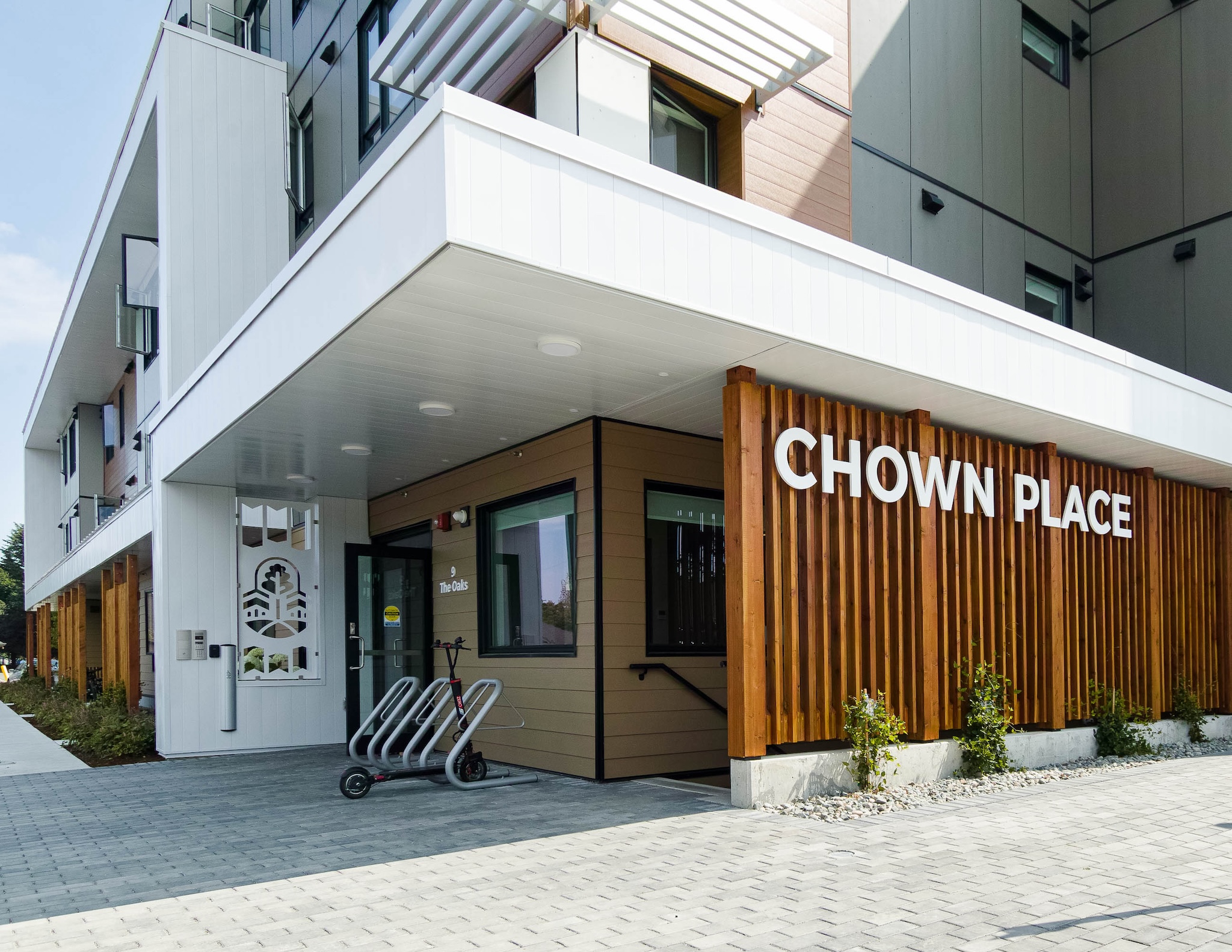 Image showing the front entrance into the building. There are floor to ceiling wooden slats covering the entryway with bright white letters spelling out "Chown Place".